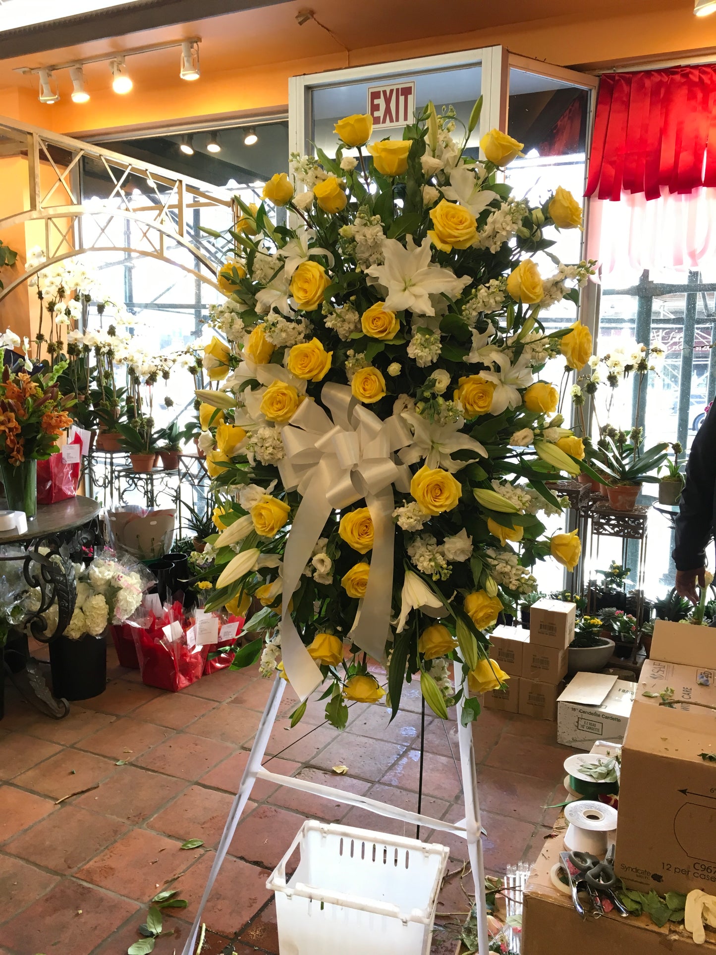 Large sympathy spray with white roses and yellow lilies on an easel