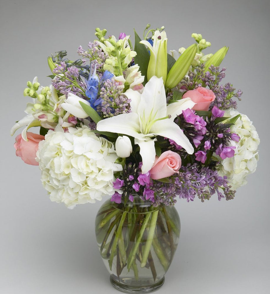 Cinderella flower arrangement with lilies, pink roses, hydrangeas, hyacinths, and snaps in a vase