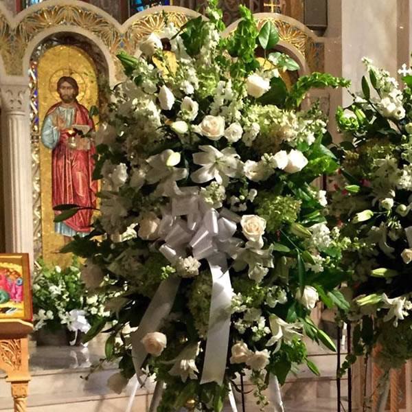 Classic round funeral wreath with greens and white roses